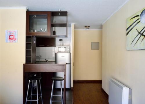 una pequeña cocina con encimera y taburetes en una habitación en Santiago Furnished Apartments, en Santiago