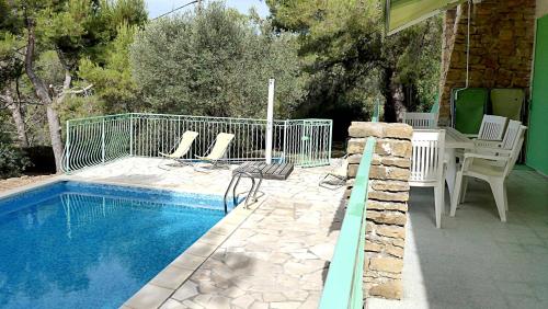 a swimming pool with chairs and a table next to a house at villa Terre Brûlée in Ceyreste