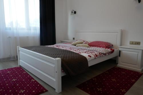 a bedroom with a white bed with red pillows at Aqualina Colibita - pe malul lacului in Colibiţa