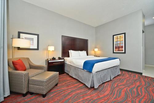 a hotel room with a bed and a chair at Holiday Inn Express & Suites Utica by IHG in Utica