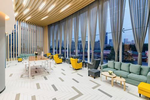 a lobby with yellow and green furniture and large windows at Holiday Inn Express Taian City Center by IHG in Tai'an