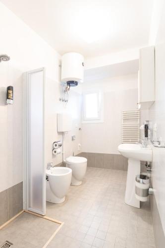 a white bathroom with two toilets and a sink at Villa Lucchese in Lignano Sabbiadoro