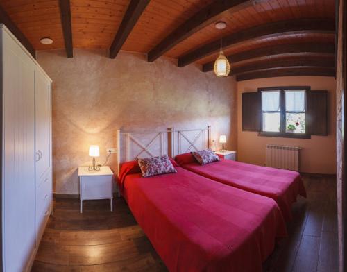 a bedroom with a large red bed and a window at Apartamentos Miradorderodiles Mirador in Villaviciosa