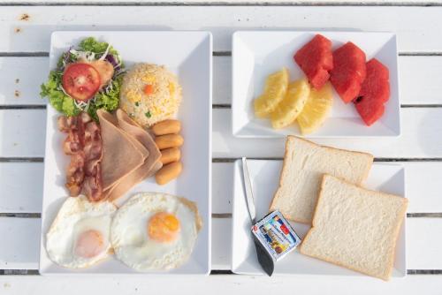 two plates of food with eggs bacon fruit and bread at Sangthian Beach Resort in Ko Samed