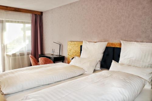 two beds in a hotel room with white pillows at Hotel Sonnenschein in Freudenstadt