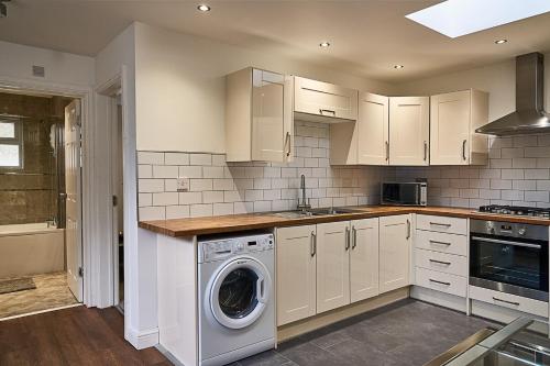 a kitchen with white cabinets and a washer at Deluxe Town Center Apartment in High Wycombe