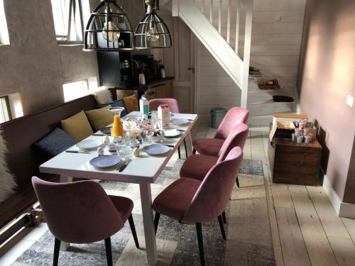 a dining room with a white table and pink chairs at B&B de Petrakerk in Rijnsburg