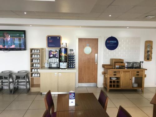 a restaurant with a table and chairs and a counter at Holiday Inn Express Nuneaton by IHG in Nuneaton
