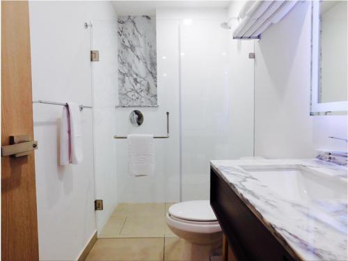 a white bathroom with a toilet and a sink at Staybridge Suites - Villahermosa Tabasco, an IHG Hotel in Villahermosa