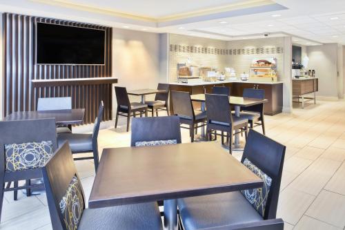 a dining room with tables and chairs and a bar at Holiday Inn Express Boston-Waltham by IHG in Waltham