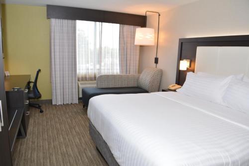 a hotel room with a large bed and a chair at Holiday Inn Express & Suites Waterville - North by IHG in Waterville