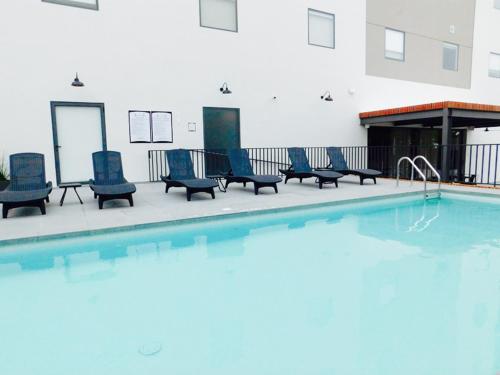 a swimming pool with blue chairs next to a building at Staybridge Suites - Villahermosa Tabasco by IHG in Villahermosa