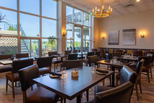 um restaurante com mesas, cadeiras e janelas em Crowne Plaza Fredericton Lord Beaverbrook, an IHG Hotel em Fredericton