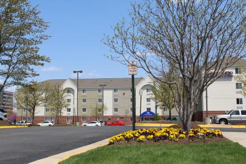 a building with a tree and flowers in front of a street at Candlewood Suites Washington-Dulles Herndon by IHG in Herndon