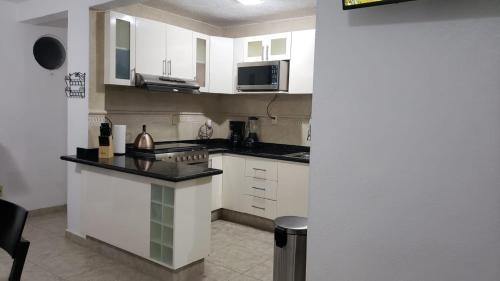 a kitchen with white cabinets and a counter top at DEPA 100 POR CIENTO FAMILIAR ACAPULCO CERCA DEL MAR CON ROFF GARDEN y JACUZZI in Acapulco