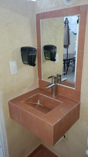 a brown sink in a bathroom with a mirror at DEPA 100 POR CIENTO FAMILIAR ACAPULCO CERCA DEL MAR CON ROFF GARDEN y JACUZZI in Acapulco
