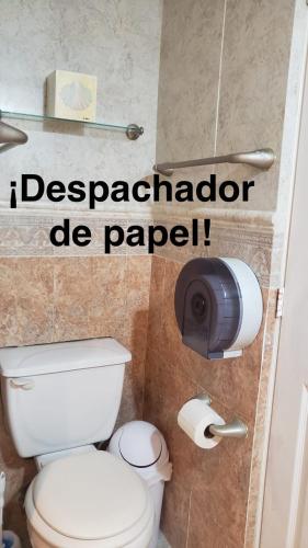 a bathroom with a toilet and a toilet paper dispenser at DEPA 100 POR CIENTO FAMILIAR ACAPULCO CERCA DEL MAR CON ROFF GARDEN y JACUZZI in Acapulco