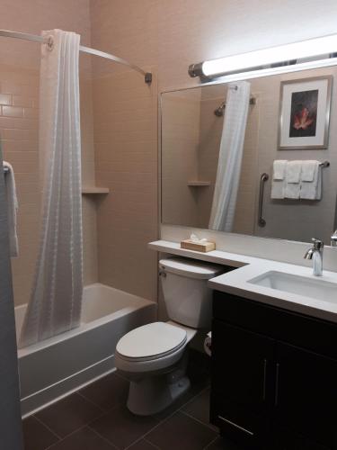 a bathroom with a toilet and a tub and a sink at Candlewood Suites Youngstown W - I-80 Niles Area by IHG in Austintown
