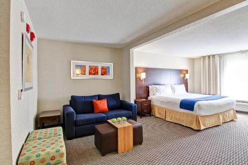 Habitación de hotel con cama y sofá azul en Holiday Inn Express Hotel & Suites Toronto - Markham, an IHG Hotel, en Richmond Hill