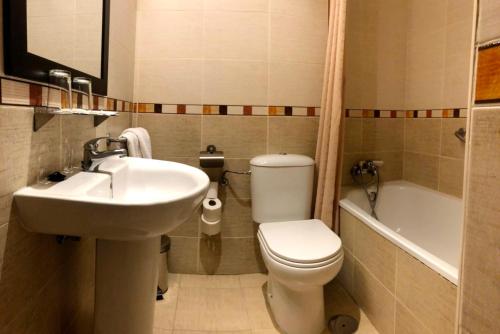 een badkamer met een toilet, een wastafel en een bad bij Hostal El Arco in Mejorada del Campo