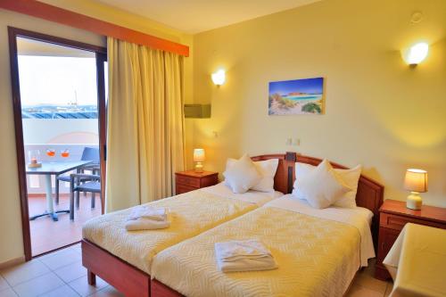 a hotel room with two beds and a balcony at Maria Beach Hotel in Kissamos