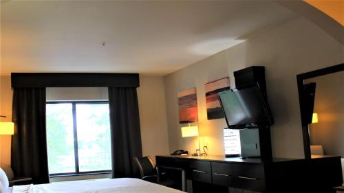 a hotel room with a bed and a desk with a television at Holiday Inn Express Hotels & Suites Rockingham West by IHG in Rockingham