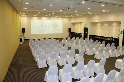 a conference room with white chairs and a projection screen at Holiday Inn Express Mérida by IHG in Mérida
