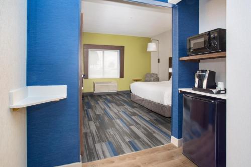 a small hotel room with a bed and a kitchen at Holiday Inn Express Kansas City - at the Legends! by IHG in Kansas City