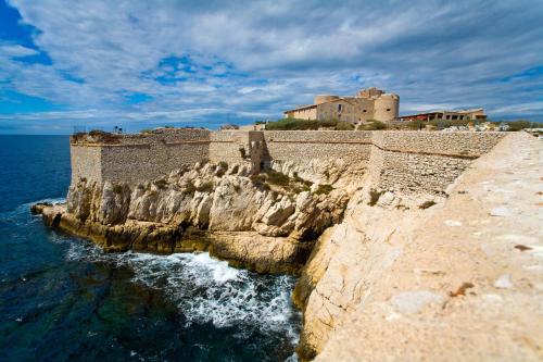 a castle on top of a cliff next to the water at Hôtel Marseille Centre Gare Saint-Charles in Marseille