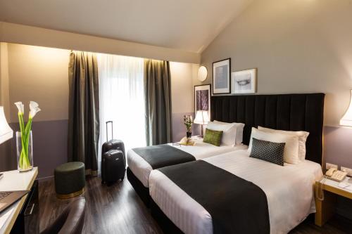 a hotel room with two beds and a desk at Holiday Inn Milan Garibaldi Station by IHG in Milan