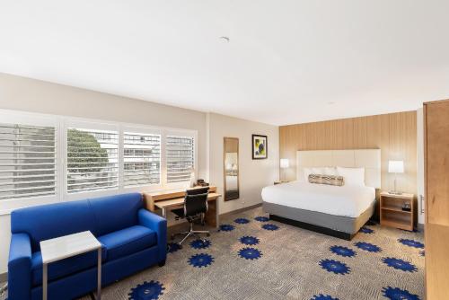 a bedroom with a bed and a desk and a blue couch at Best Western Red Coach Inn in San Francisco