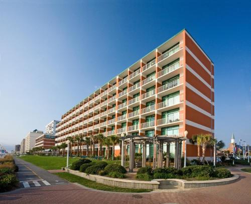 a tall building with palm trees in front of it at Holiday Inn & Suites Virginia Beach - North Beach by IHG in Virginia Beach