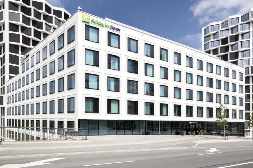 a white building with windows on the side of a street at Holiday Inn Express Munich City West by IHG in Munich