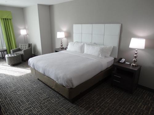 a large bed in a hotel room with two lamps at Holiday Inn Covington by IHG in Covington