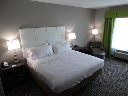 a hotel room with a large bed and a chair at Holiday Inn Covington by IHG in Covington