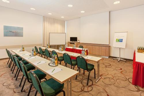 a conference room with long tables and green chairs at Holiday Inn Express Nürnberg-Schwabach in Schwabach