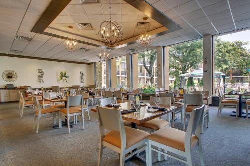 a dining room with tables and chairs and windows at Holiday Inn Westbury-Long Island by IHG in Carle Place