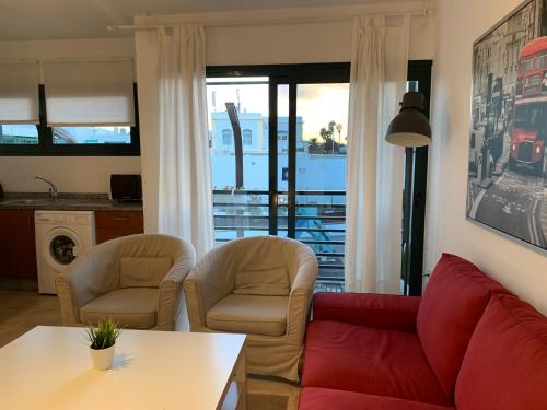 sala de estar con sofá rojo y 2 sillas en La Botavara Apartment, en Playa Blanca