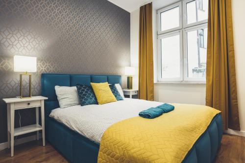 a bedroom with a blue bed and a window at FatCat Apartments in Krakow