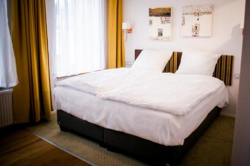 a bedroom with a bed with white sheets and a window at Salon Win Wine Bar & Apartments in Jasło