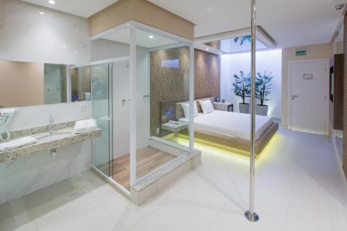 a bathroom with a glass shower and a bed at MOTEL CLASS in Alagoinhas