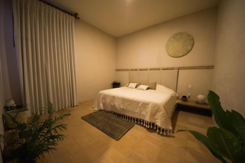 a bedroom with a white bed and a plant at Casa Montore by Barrio Mexico in Guadalajara