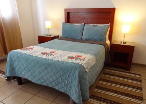 a bedroom with a bed with a blue comforter at Hotel San Miguel Penjamo in Pénjamo
