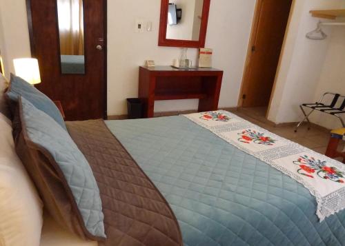 a bedroom with a bed with a blue comforter at Hotel San Miguel Penjamo in Pénjamo