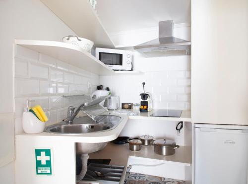 een kleine keuken met een spoelbak en een magnetron bij Alfama Apartment in Lissabon