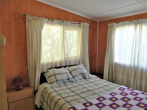 Un dormitorio con una cama y dos ventanas en Cabana Caburgua, en Caburgua