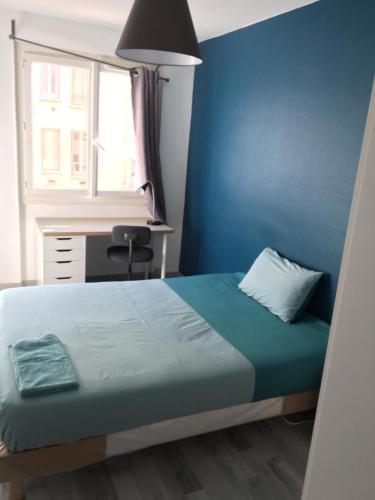 une chambre avec un lit, un bureau et une fenêtre dans l'établissement Eden Host, à Clermont-Ferrand