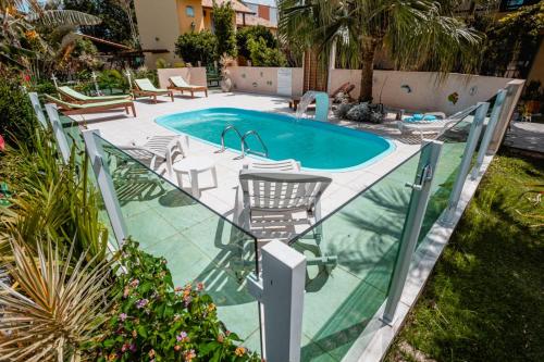 a swimming pool with chairs and a table and a swimming pool at Pousada Santa Genoveva campeche in Florianópolis