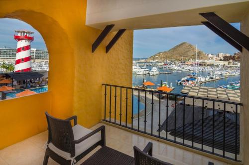 a balcony with a lighthouse and boats in the water at Hotel Tesoro Los Cabos in Cabo San Lucas