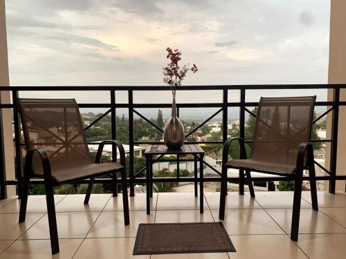 un balcón con 2 sillas y una mesa con un jarrón. en Beautiful apartment, Terrace with incredible view, 3 bdr, Escalon, Exclusive, Secure, en San Salvador